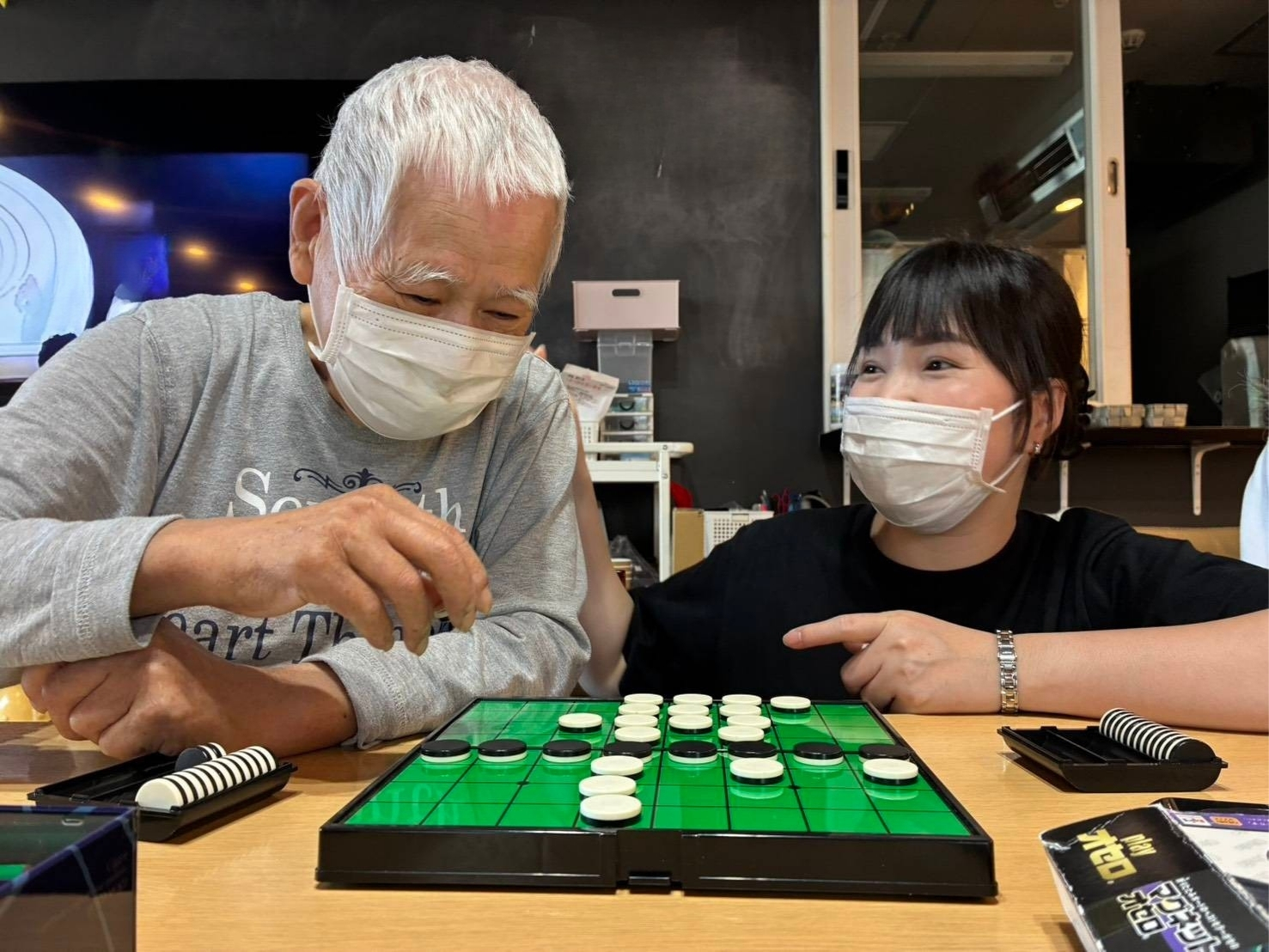 Comrade清水町のデイサービスで、職員とご利用者様がオセロを楽しみながら交流する様子